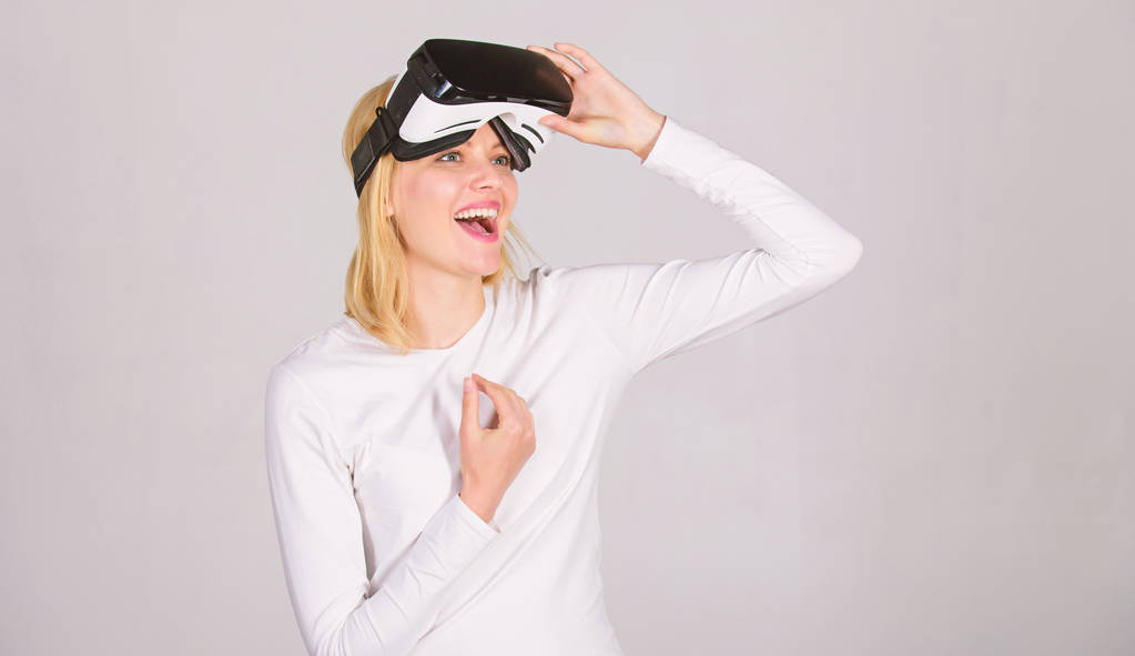 Young woman using a virtual reality headset. Amazed young woman touching the air during the VR experience. Confident young woman adjusting her virtual reality headset and smiling. - Photo, Image