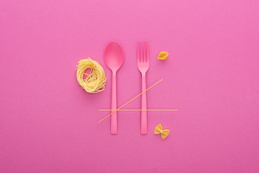 cuillère et fourchette en plastique rose à proximité de différents types de pâtes isolées sur rose
 - Photo, image