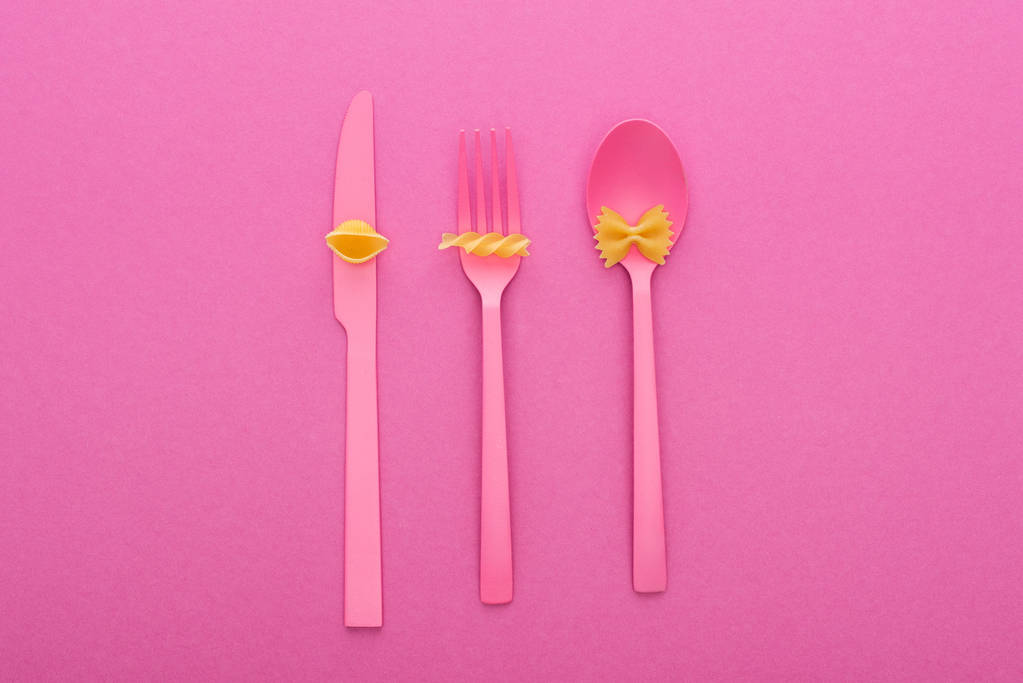 top view of different kinds of pasta on pink plastic cutlery isolated on pink - Photo, Image