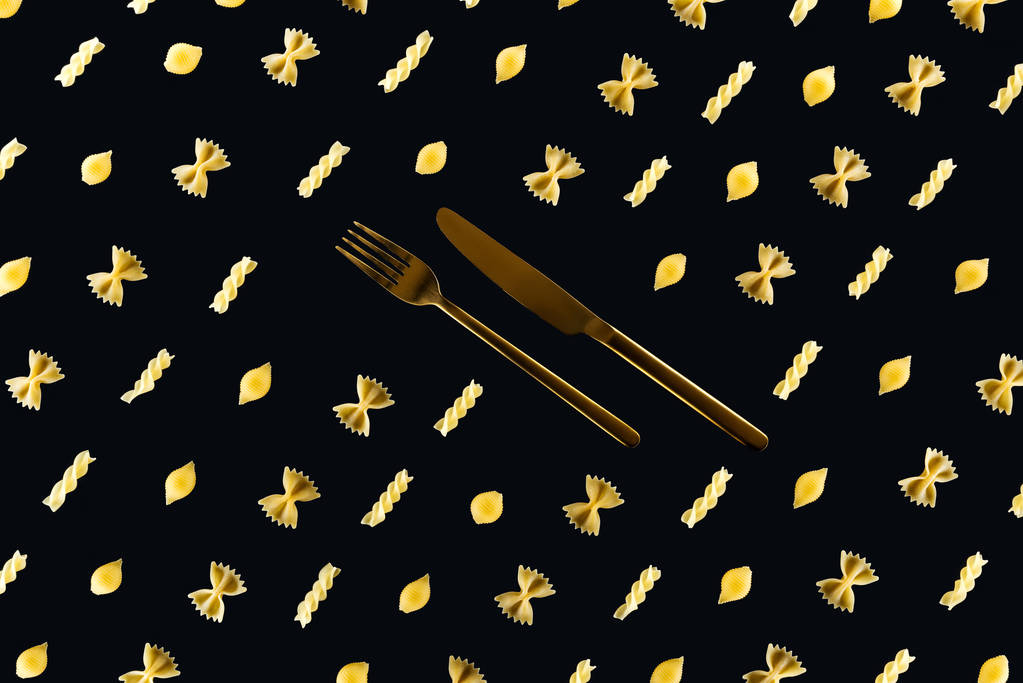 flat lay of different kinds of pasta with metal cutlery in middle isolated on black - Photo, Image