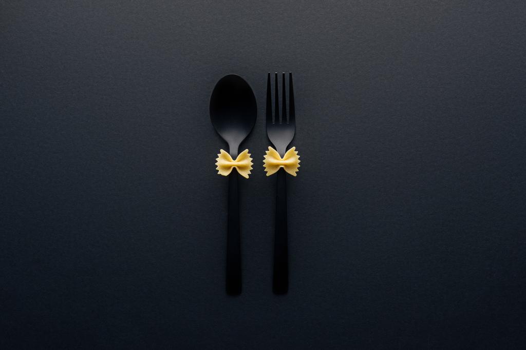 főzés nélküli Farfalle tészta, műanyag kanál és Villa izolált fekete - Fotó, kép