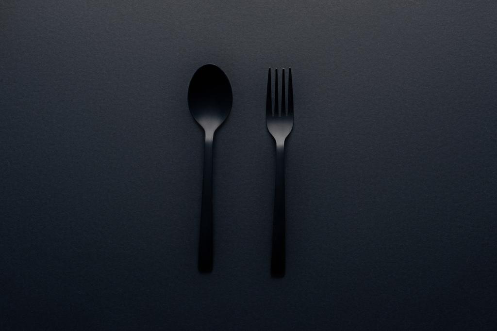vista dall'alto di cucchiaio di plastica e forchetta su sfondo nero
 - Foto, immagini