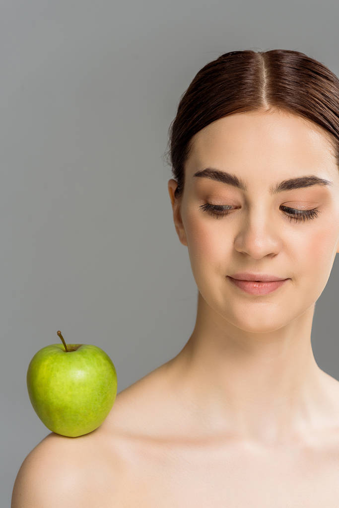 brunette alaston nainen vihreä omena olkapäällä eristetty harmaa
  - Valokuva, kuva
