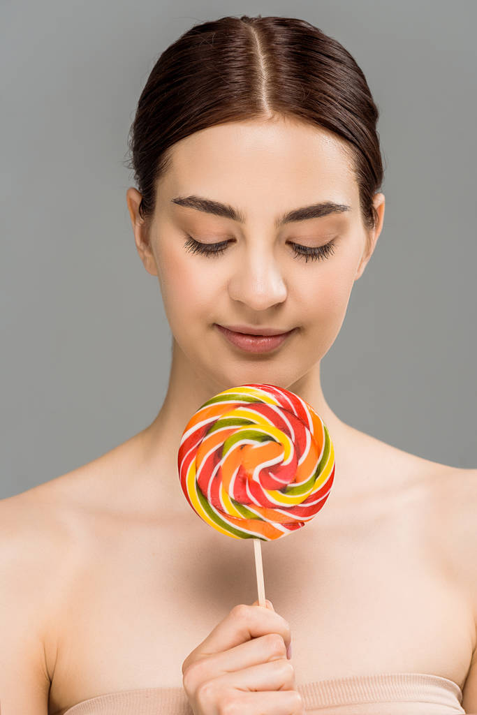 cheerful young woman holding colorful lollipop isolated on grey  - Photo, Image