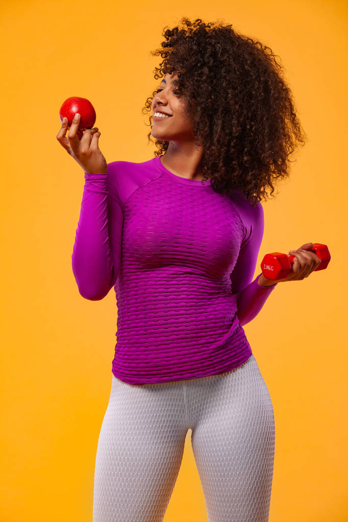 Sportif uygun kadın, kırmızı elma ve Dambıl ile atlet beyaz arka planda fitness egzersiz yapar. Fitness ve çalışma motivasyonu. - Fotoğraf, Görsel