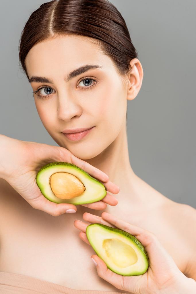 beautiful young woman holding avocado halves isolated on grey  - Photo, Image