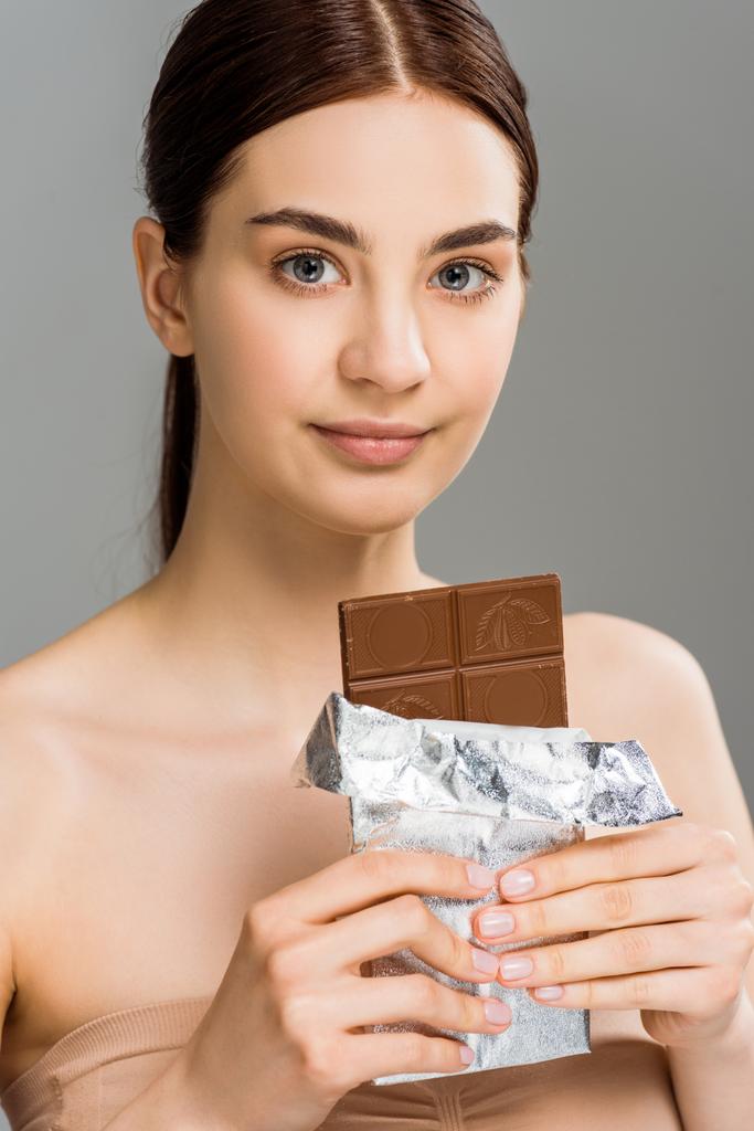 attrayant jeune femme tenant barre de chocolat isolé sur gris
  - Photo, image