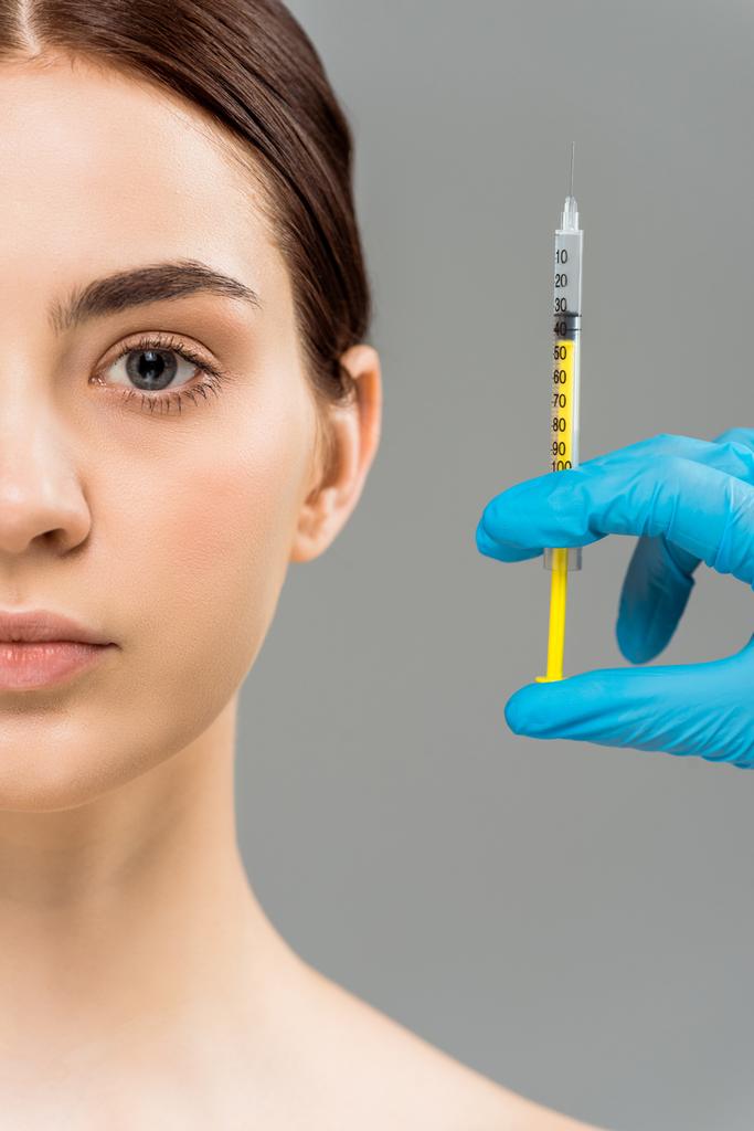 vista recortada de cirurgião plástico segurando seringa perto de mulher nua isolada em cinza
  - Foto, Imagem