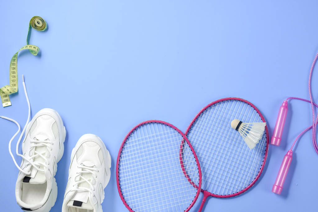 Sport flat lag met shuttle en badminton racket, springtouw, sneakers en meetlint op paarse achtergrond. Fitness, sport en gezond lifestyle concept. - Foto, afbeelding