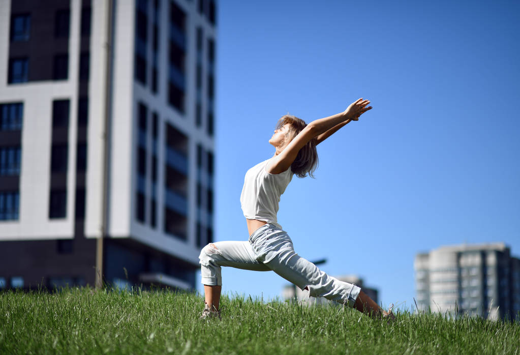 Nuori nainen tekee jooga venyttely harjoituksia modernin kaupungin puistossa
 - Valokuva, kuva