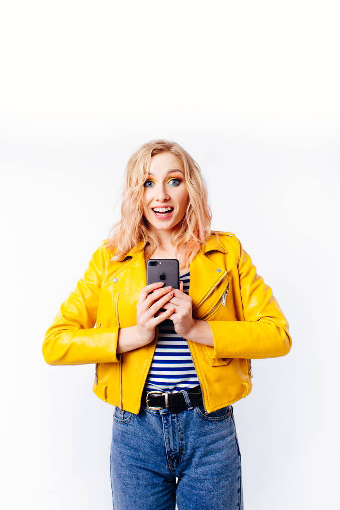 Chica en una chaqueta de color amarillo brillante hace una selfie para las redes sociales en el teléfono inteligente
. - Foto, imagen