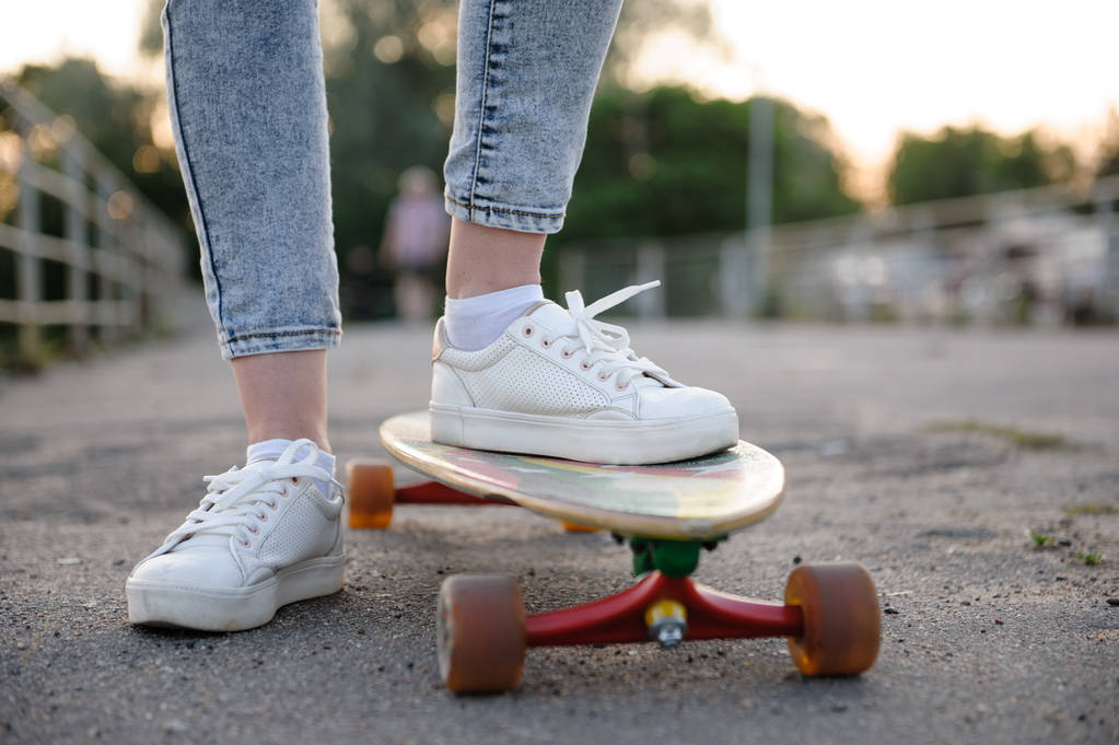 Κορίτσι με το μακρύ σανίδα φορώντας αθλητικά παπούτσια σε αστικό στυλ - Φωτογραφία, εικόνα