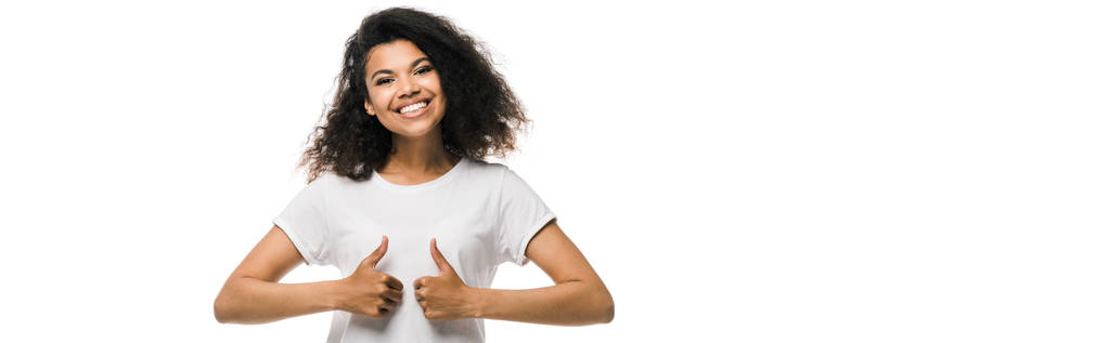 白で孤立した親指を示すカーリーと肯定的なアフリカ系アメリカ人女性のパノラマショット  - 写真・画像