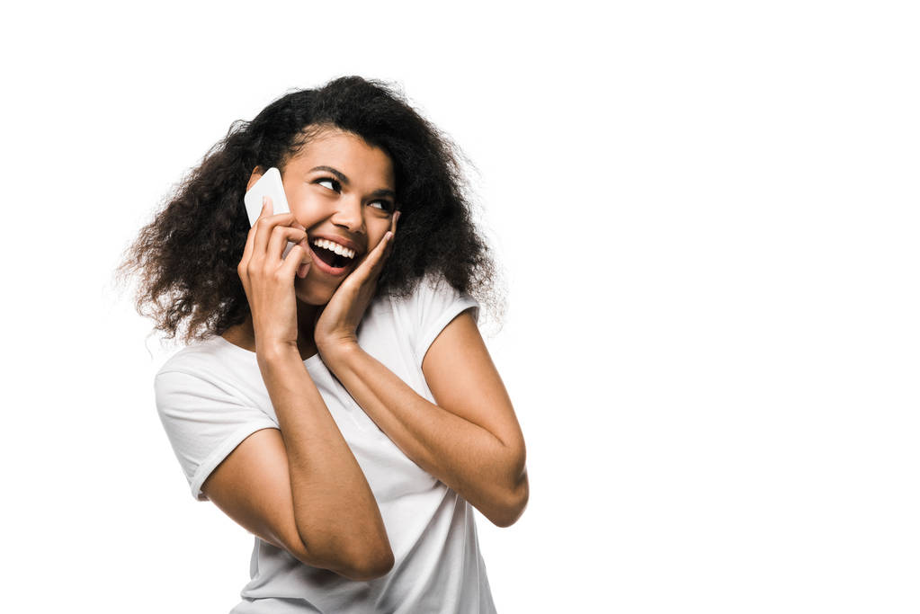 χαρούμενη αφρικανική Αμερικάνικη κοπέλα που μιλάει στο smartphone απομονώνεται σε λευκό  - Φωτογραφία, εικόνα