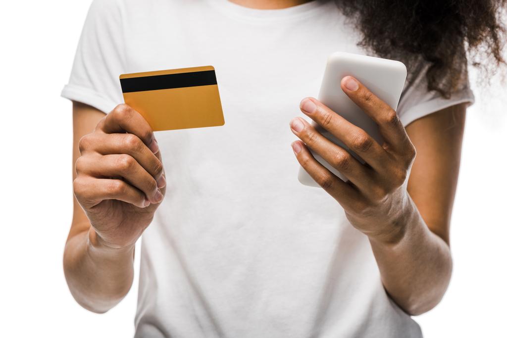 cropped view of african american woman holding credit card near smartphone isolated on white  - Photo, Image