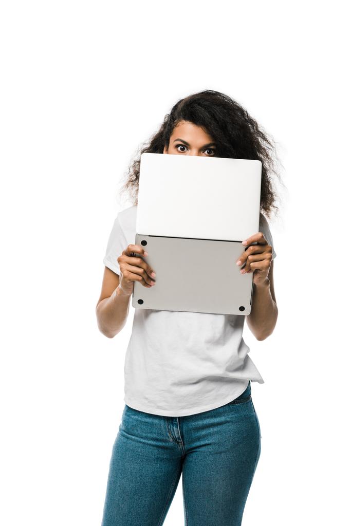 krullend Afrikaans Amerikaans meisje bedekt gezicht met laptop geïsoleerd op wit  - Foto, afbeelding