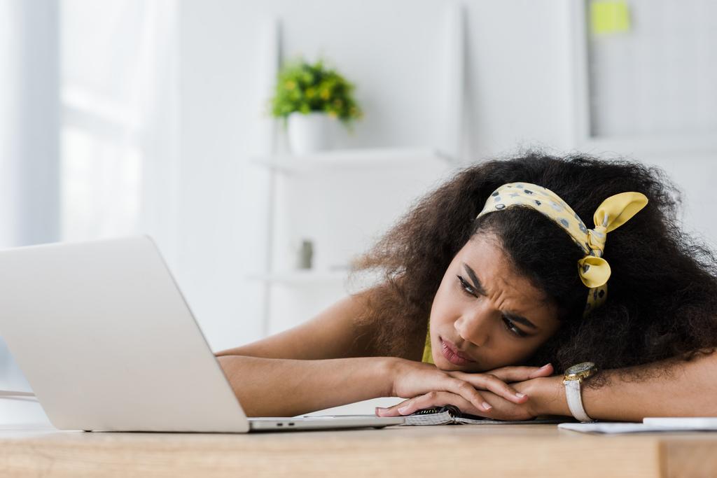 moe Afro-Amerikaanse vrouw liggend op tafel en kijken naar laptop  - Foto, afbeelding
