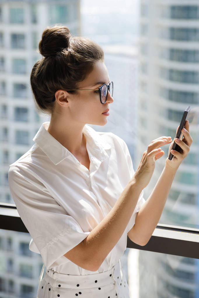 Молодая деловая женщина использует смартфон в своем офисе
 - Фото, изображение