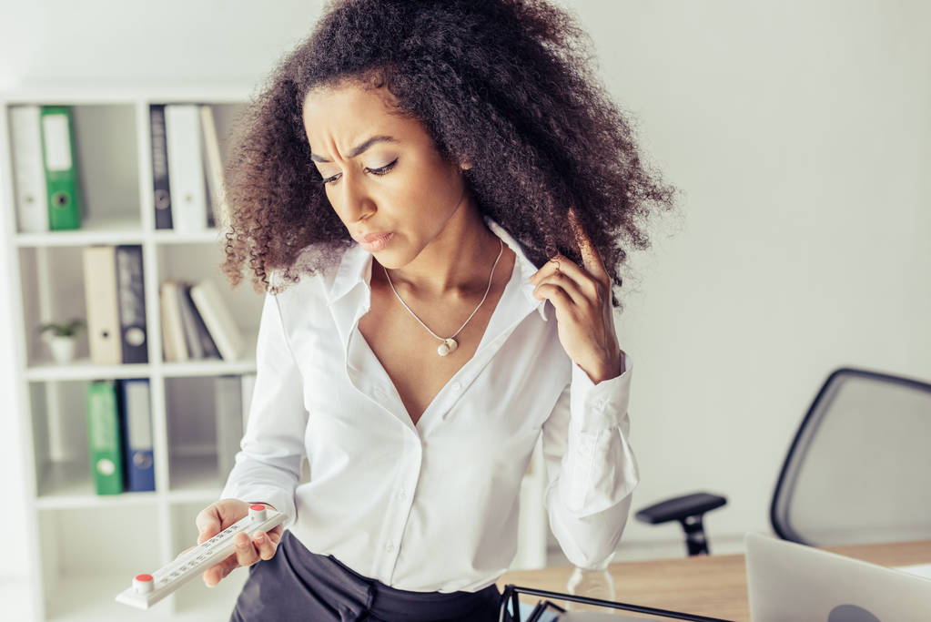 mulher de negócios afro-americana insatisfeita olhando o termômetro no escritório
 - Foto, Imagem