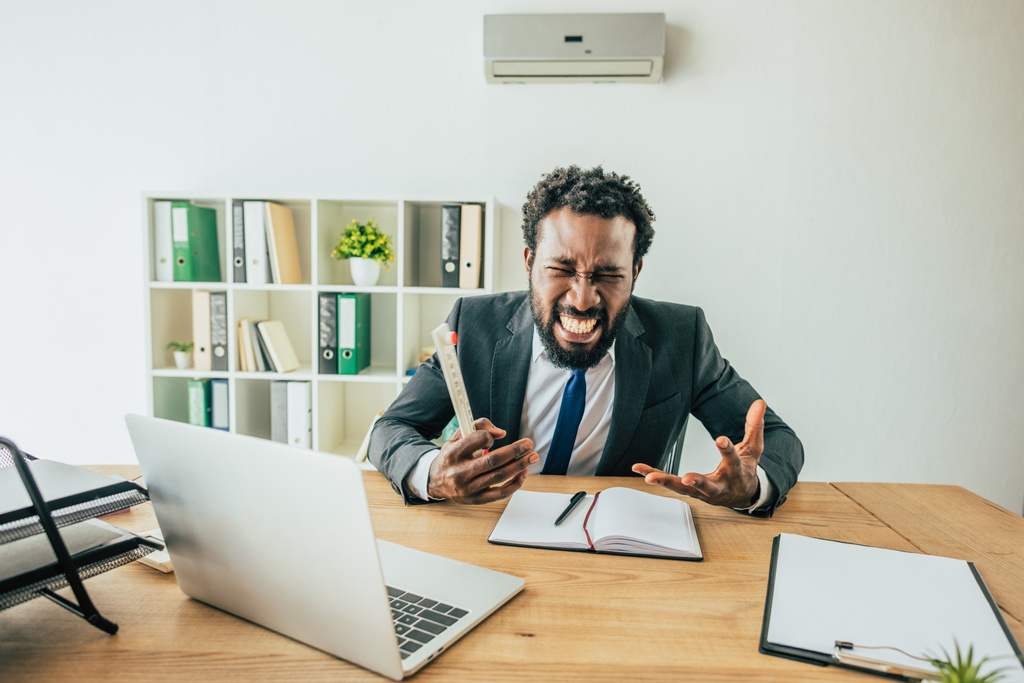 irritado empresário afro-americano segurando termômetro e gestos enquanto sentado no local de trabalho no escritório
 - Foto, Imagem