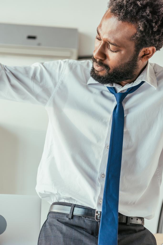 вичерпаний афроамериканець бізнесмен страждає від спеки влітку і дивлячись на спітнілий сорочку - Фото, зображення