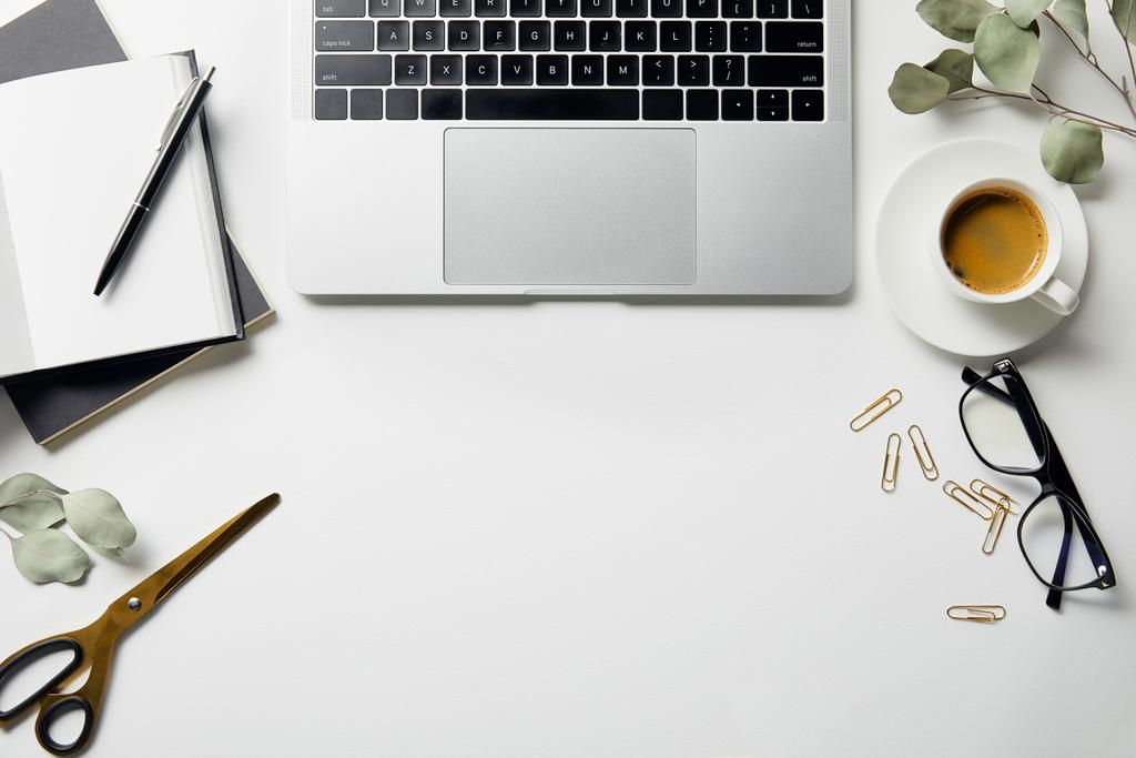 tollas, irodaszerek, olló, laptop, kávé, poharak és notebookok felülnézete fehér felületen lévő tollal - Fotó, kép