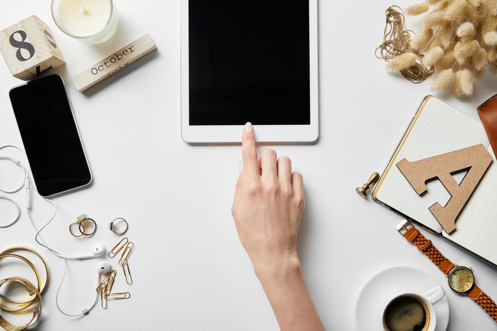 vista ritagliata della donna utilizzando tablet digitale su superficie bianca con piante, cancelleria, gioielli, blocco note e caffè
 - Foto, immagini