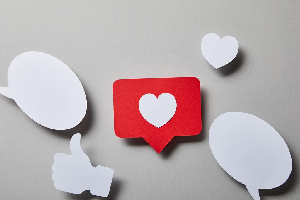 roodachtige kaart, tekstballonnen, duim omhoog en klein papier hart op wit oppervlak - Foto, afbeelding