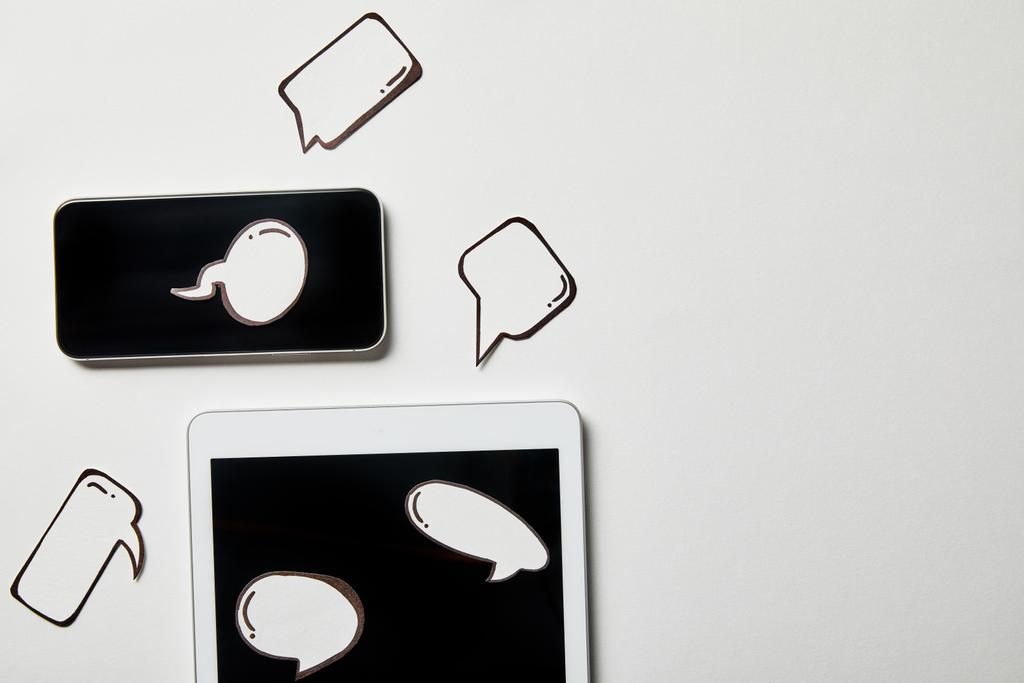 digitaalinen tabletti ja älypuhelin paperilla ajattelun ja puheen kuplia valkoisella pinnalla
 - Valokuva, kuva