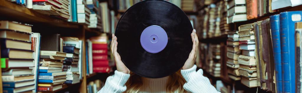 Panoramaaufnahme einer jungen erwachsenen Frau mit Vinyl in der Bibliothek  - Foto, Bild