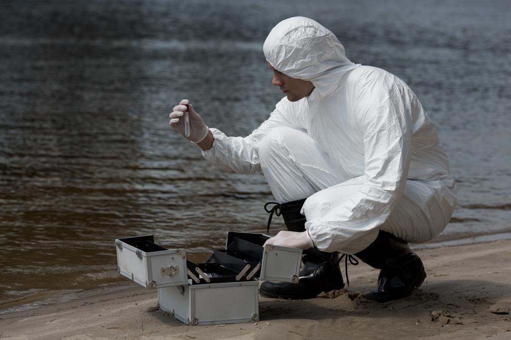 inspetor de água em luvas de látex e kit de inspeção de abertura de fantasia protetora na costa arenosa
 - Foto, Imagem
