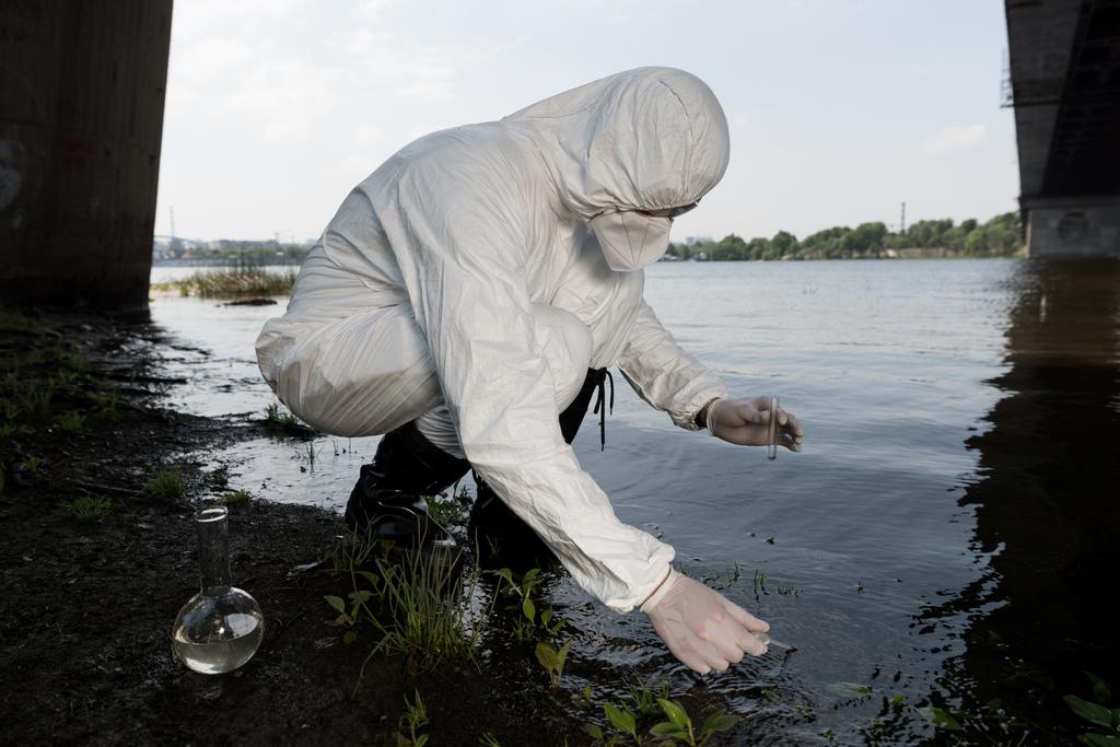 inspecteur de l'eau en costume de protection et respirateur prélèvement d'échantillon d'eau à la rivière
 - Photo, image