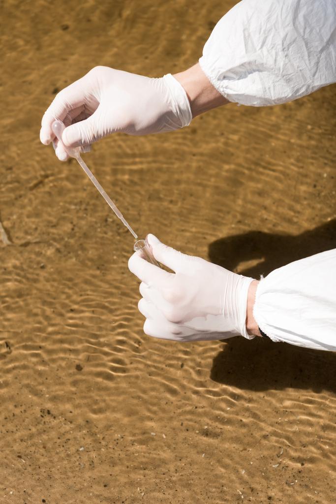 川で水サンプルを採取するラテックス手袋の水検査官の部分的な眺め - 写真・画像