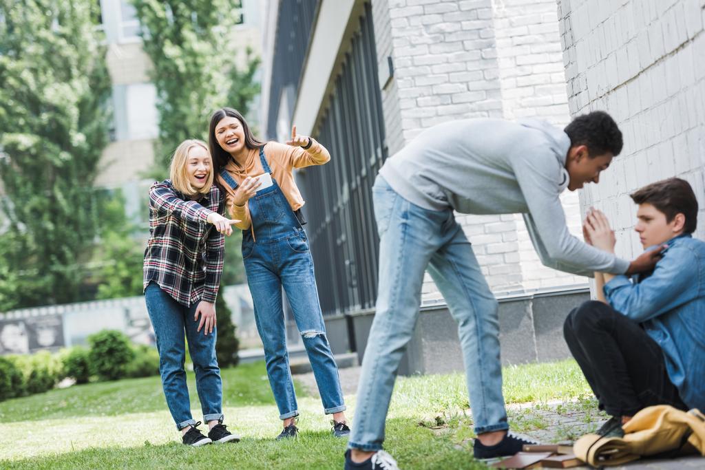 Afrikanisch-amerikanischer Junge in Kapuzenpulli und Jeans Bulling Junge und Teenager schießen es und zeigt mit den Fingern  - Foto, Bild