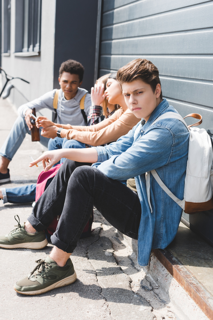 adolescents assis, buvant de la bière dans une bouteille en verre et tenant une cigarette
 - Photo, image