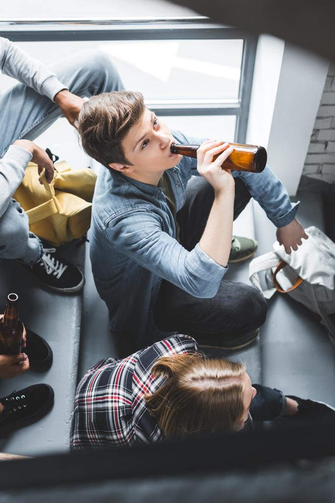 высокий угол обзора подростков, сидящих на лестнице и пьющих пиво
  - Фото, изображение