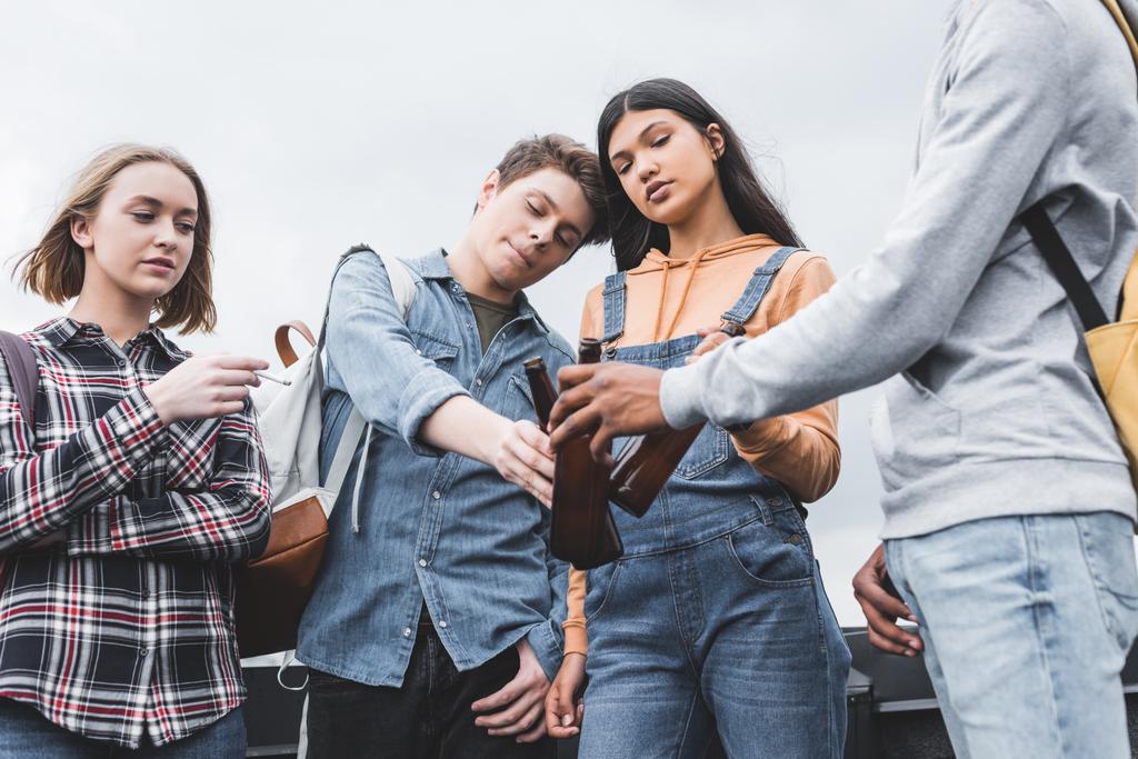 Teenageři cinukuje skleněnými lahvemi a kouřící cigaretu na střeše  - Fotografie, Obrázek