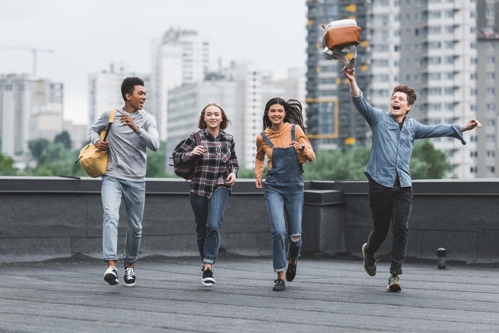 playful and happy teenagers running and smiling on roof  - Photo, Image