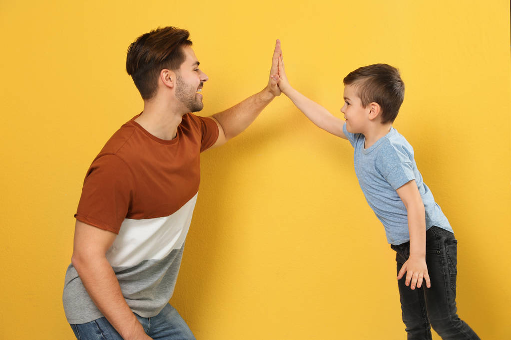 Portrait of dad and his son giving high five on color background - Photo, Image