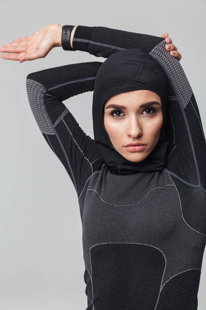 junge Frau Fitness Muslim machen Dehnübungen isoliert über weiße Wand Hintergrund. - Foto, Bild