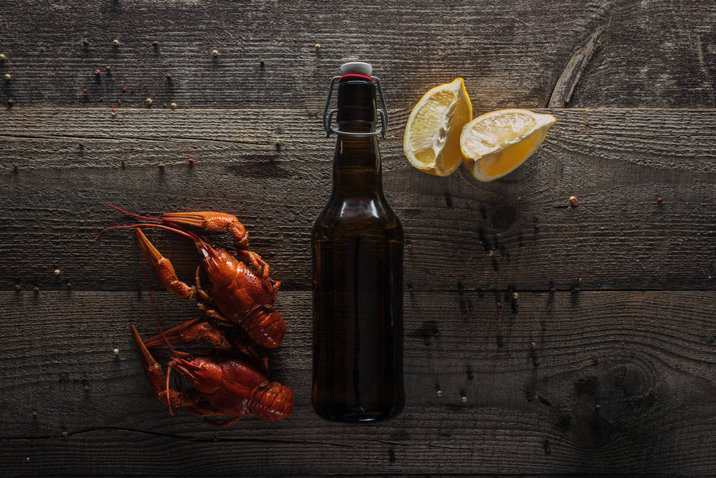 vista superior de langostas rojas, rodajas de limón y botella con cerveza en la superficie de madera
 - Foto, imagen