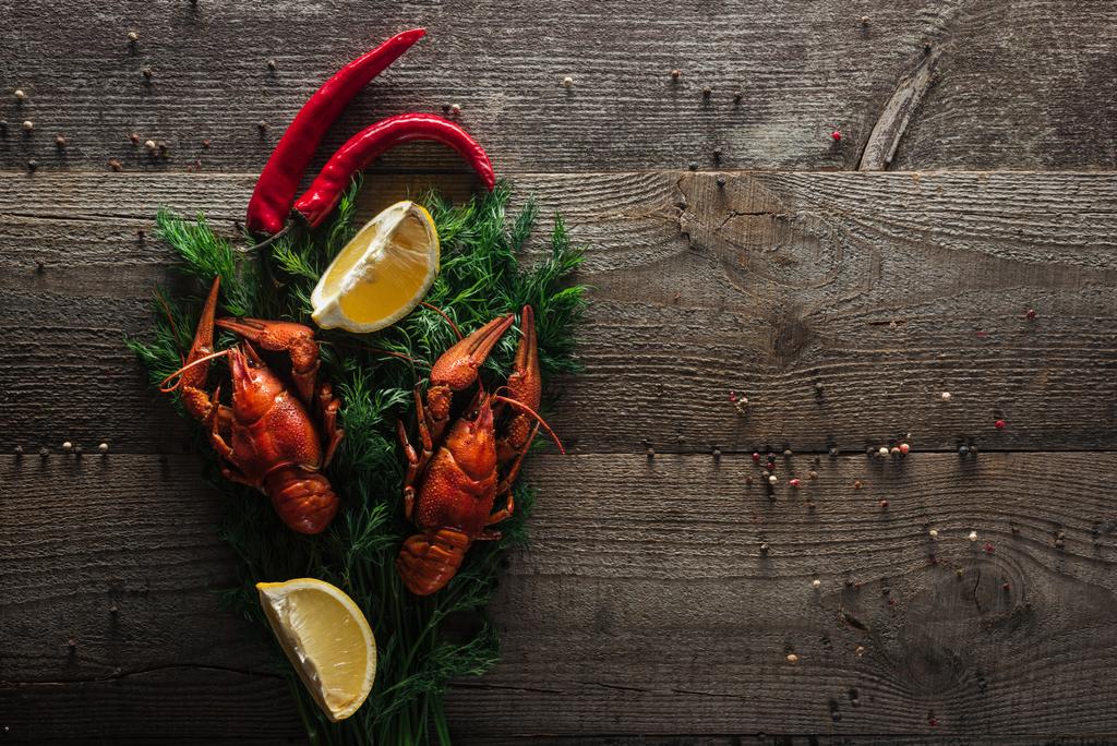 top view of red lobsters, lemon slices, pepper and dill on wooden surface - Photo, Image