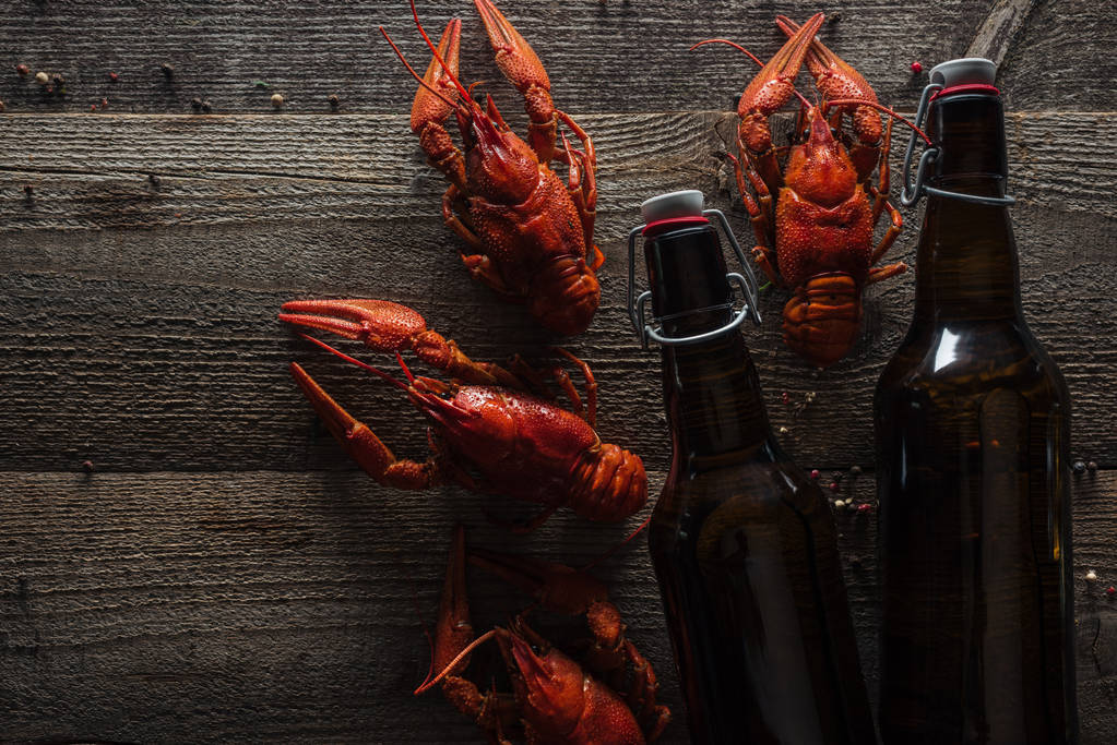 top view of red lobsters and bottles with beer on wooden surface - Photo, Image