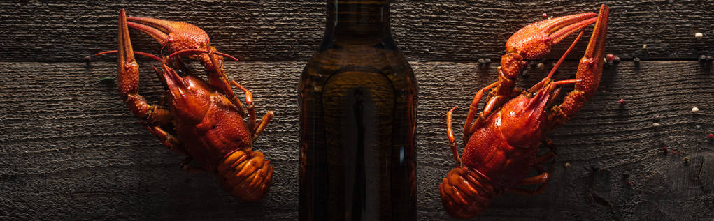 foto panoramica di aragoste rosse e bottiglia di vetro con birra sulla superficie in legno
 - Foto, immagini
