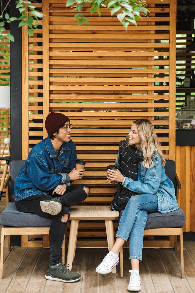 屋外のカフェで笑顔のマルチエスニックカップル - 写真・画像