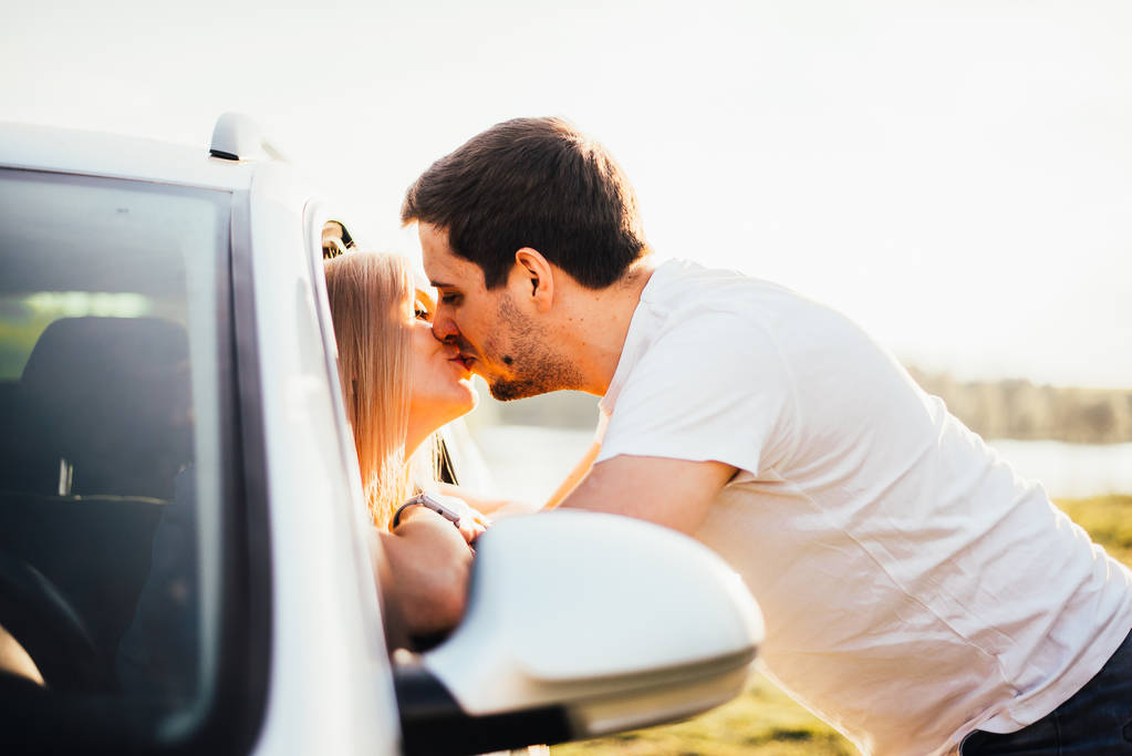 Schönes junges Paar küsst sich während der Fahrt durchs Autofenster - Foto, Bild