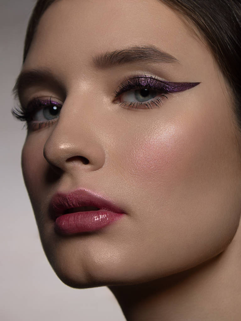 A close-up portrait of beauty with beautiful fashionable evening make-up, black snares on the eyes and extremely long eyelashes. pink lipstick on the lips. Cosmetology and spa facial skin care - Photo, Image