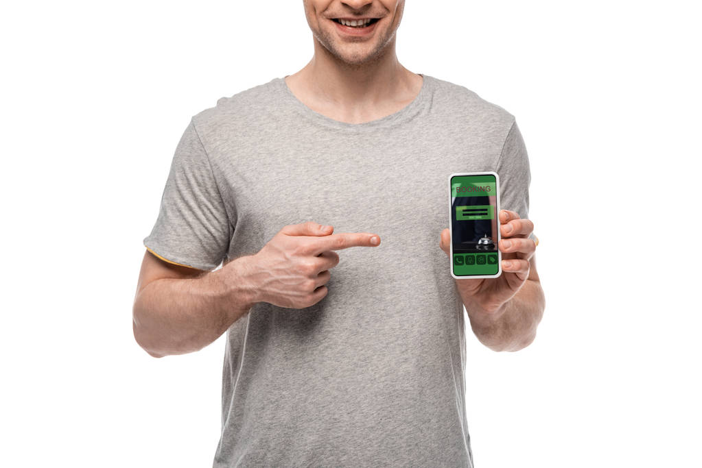 cropped view of man pointing at smartphone with booking app, isolated on white - Photo, Image