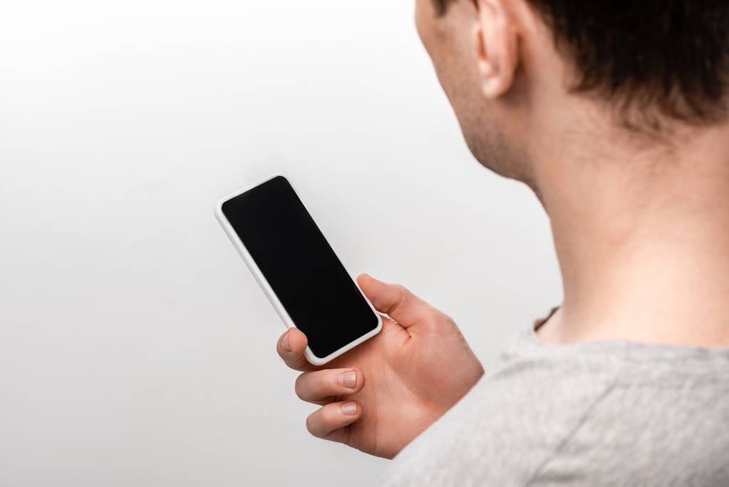 vista ritagliata dell'uomo che tiene smartphone con schermo vuoto isolato sul grigio
 - Foto, immagini