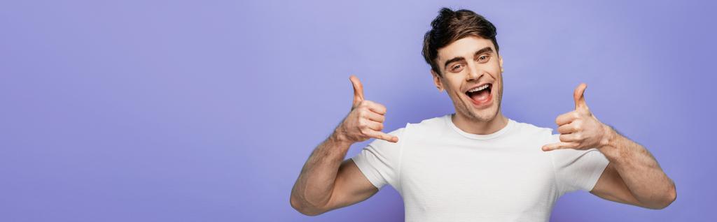 panoramic shot of cheerful man showing lets drink gestures and smiling at camera on blue background - Photo, Image